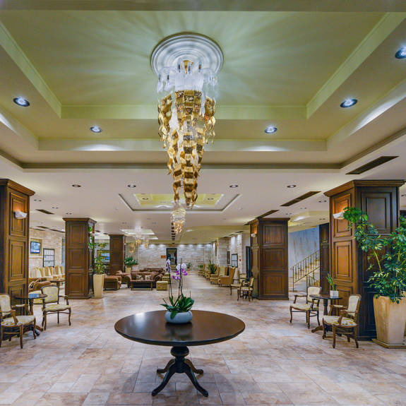 Hotel lobby with large plant pots, chairs, couches and wooden tables