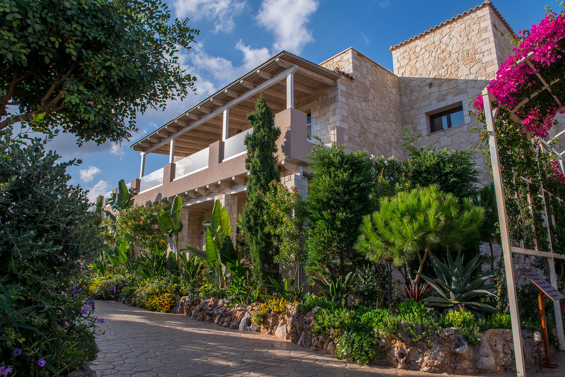 Ξενοδοχείο με πέτρινους τοίχους και κήπους, κάτω από τον μπλε ουρανό, στην Σταλίδα Κρήτη