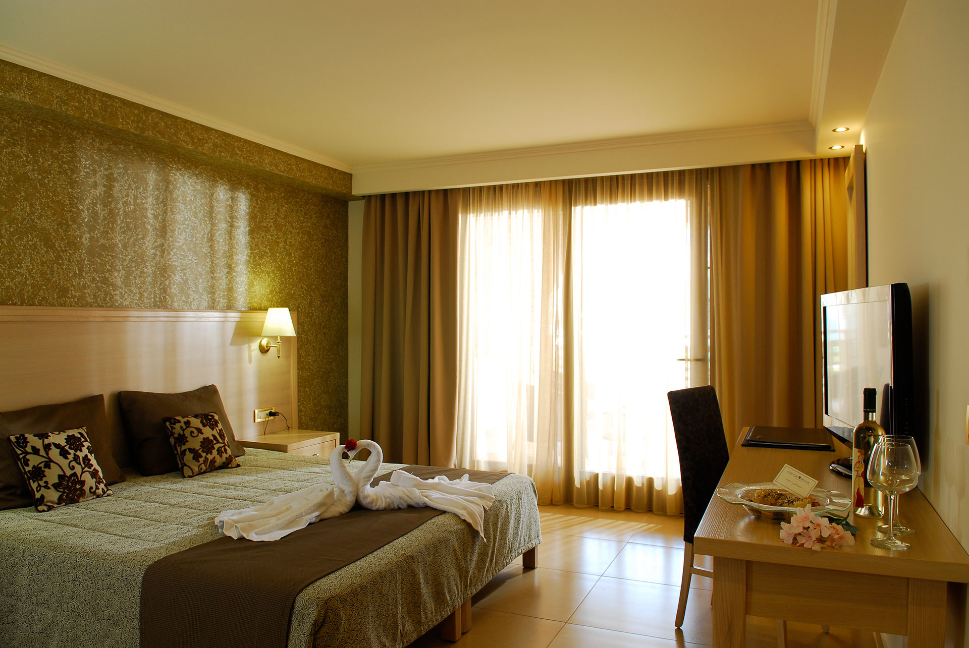 Δωμάτιο ξενοδοχείου με διπλό κρεβάτι χρώματος άσπρου και πρασίνου μαζί με τραπέζι 