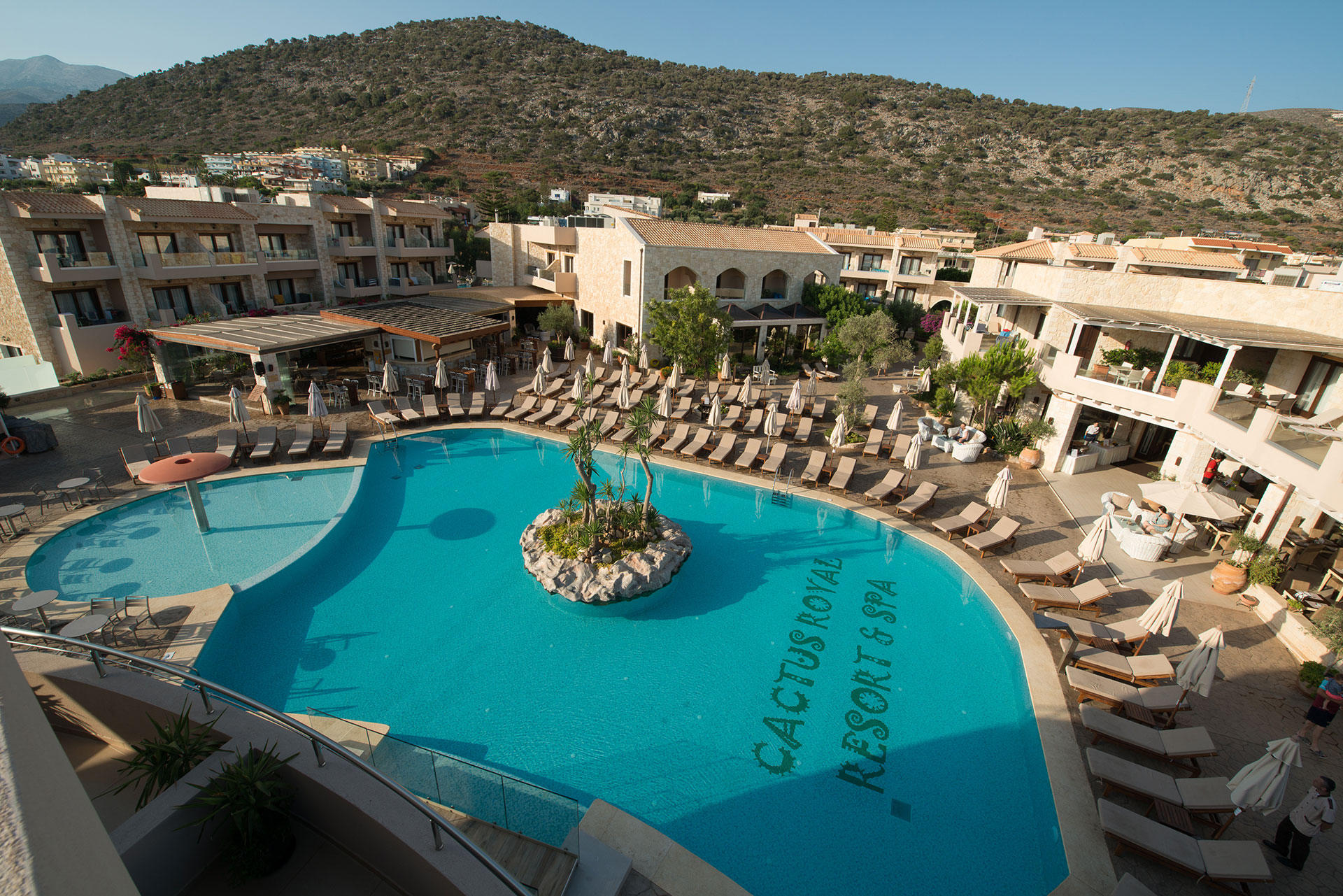 Aerial view of a hotels' main swimming pool, with small islet in the middle, and separate pool for kids