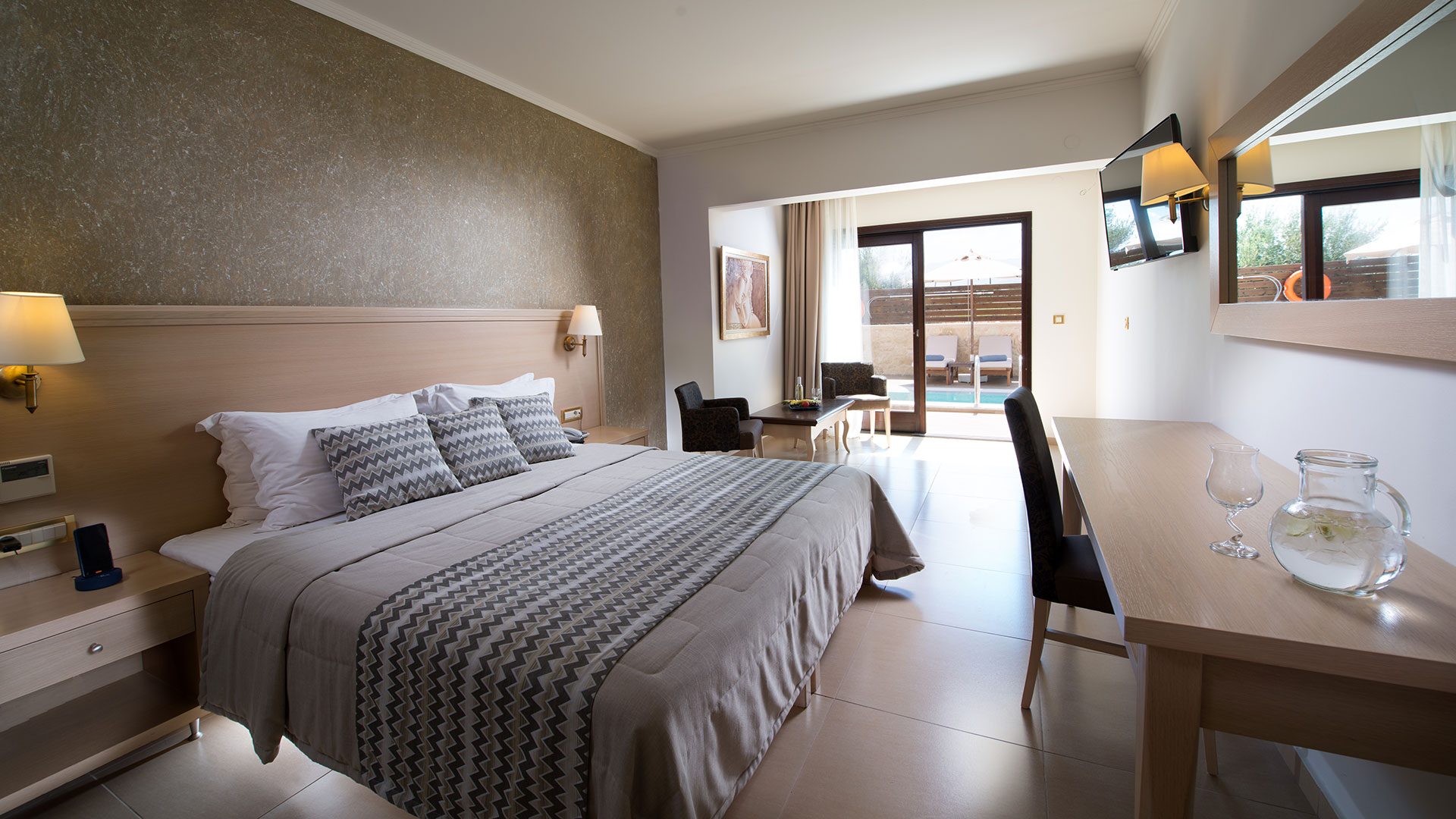 Interior view of a hotel room with a white double bed with gray wallpaper and a brown coffee table