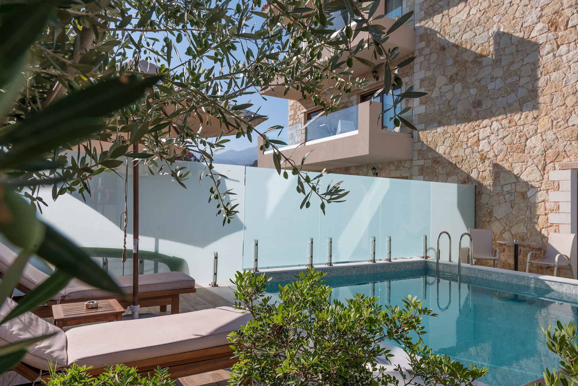 Πετρόχτιστο ξενοδοχείο με πισίνα που έχει δύο ξαπλώστρες και θέα τον ουρανό