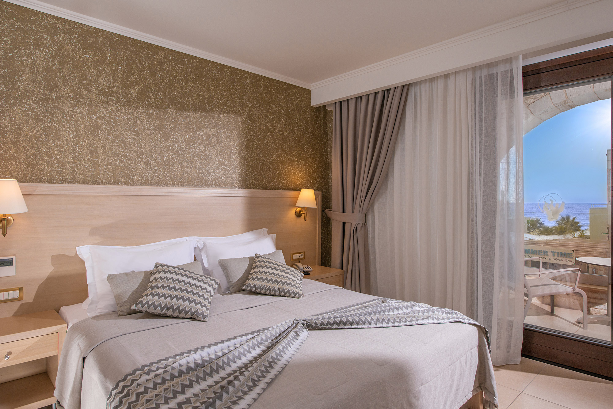 Hotel room with a gray and green double bed with a balcony in the morning