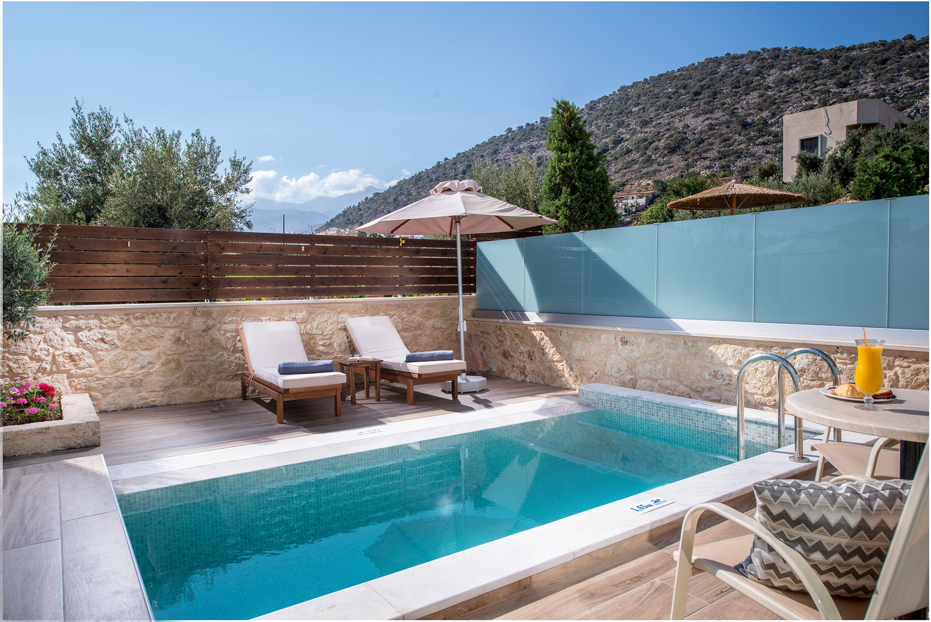 Όψη πισίνας με θέα το βουνό, τον ουρανό με ένα σετ ξαπλώστρας και τραπεζάκι 