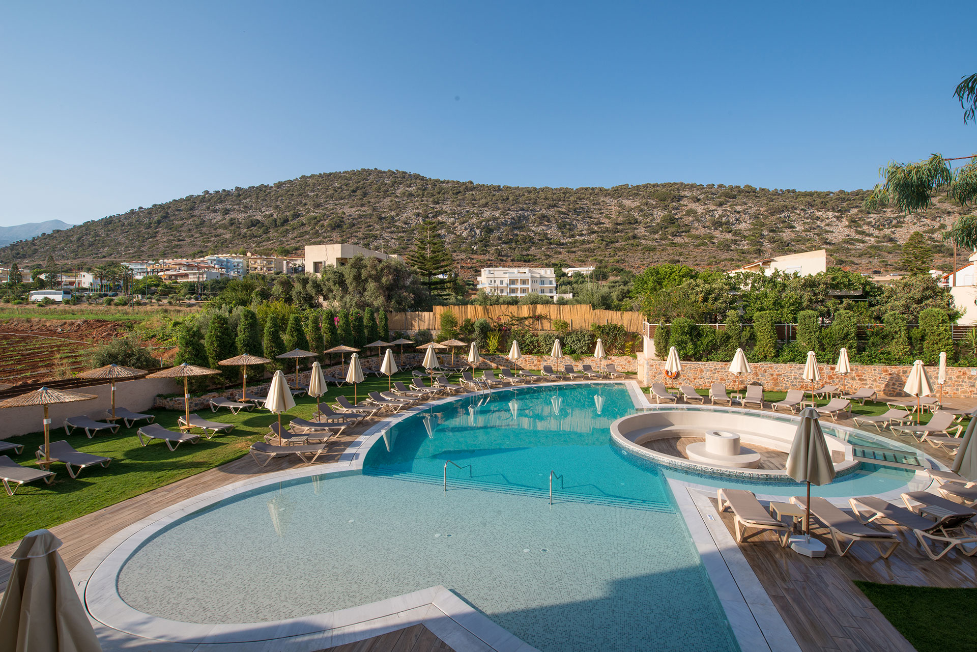 Aerial view of a hotel swimming pool in front of mountains and trees